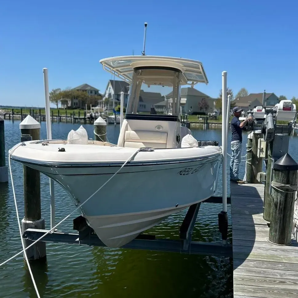 Center-console boat on a lift with a technician at the motor