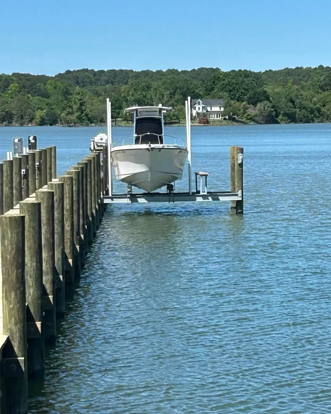 Center-console boat on a lift at the end of a long pier