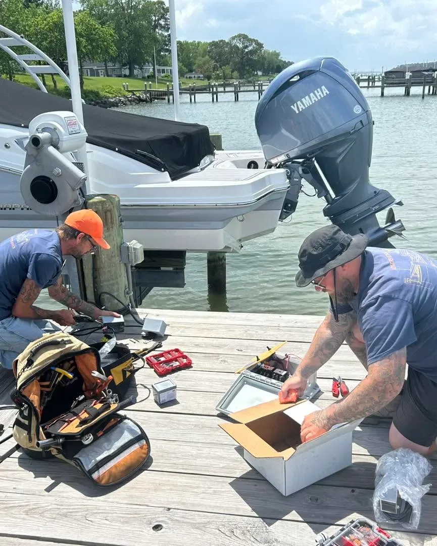 Crew wiring a new lift motor beside a boat