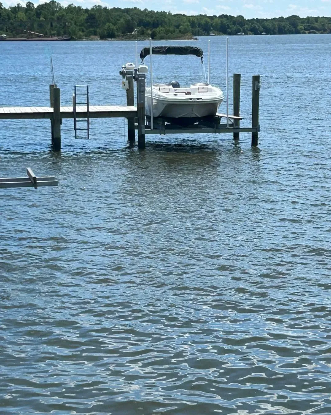 Deck boat on a lift beside a pier ladder