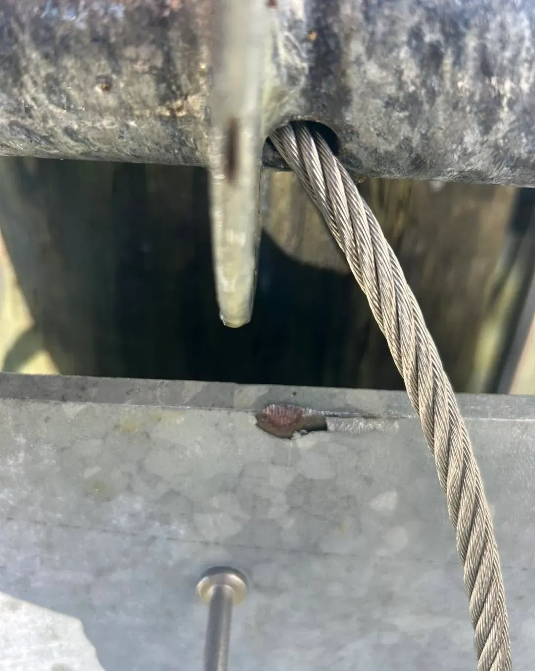Frayed boat lift cable running over a worn pulley