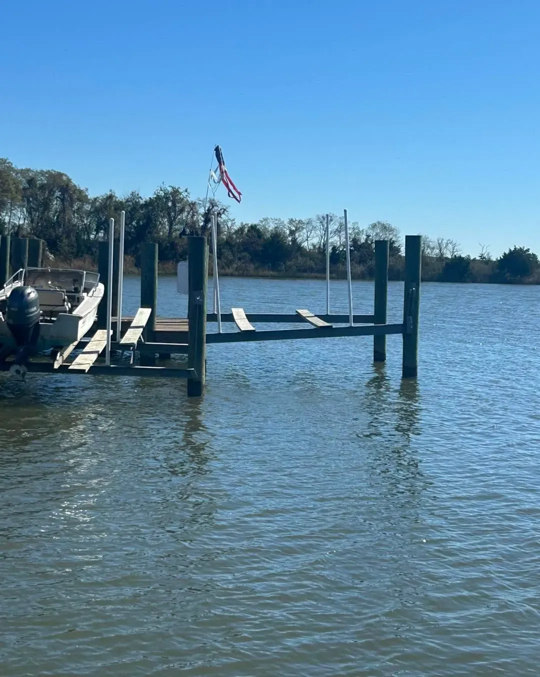 Two boat lifts at a pier on a wide river