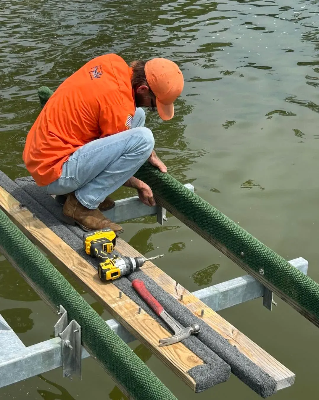 Technician in an orange cap installing a carpeted bunk on a lift