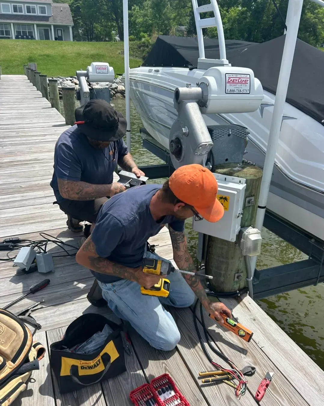 Technician wiring a lift control box on a dock beside a boat