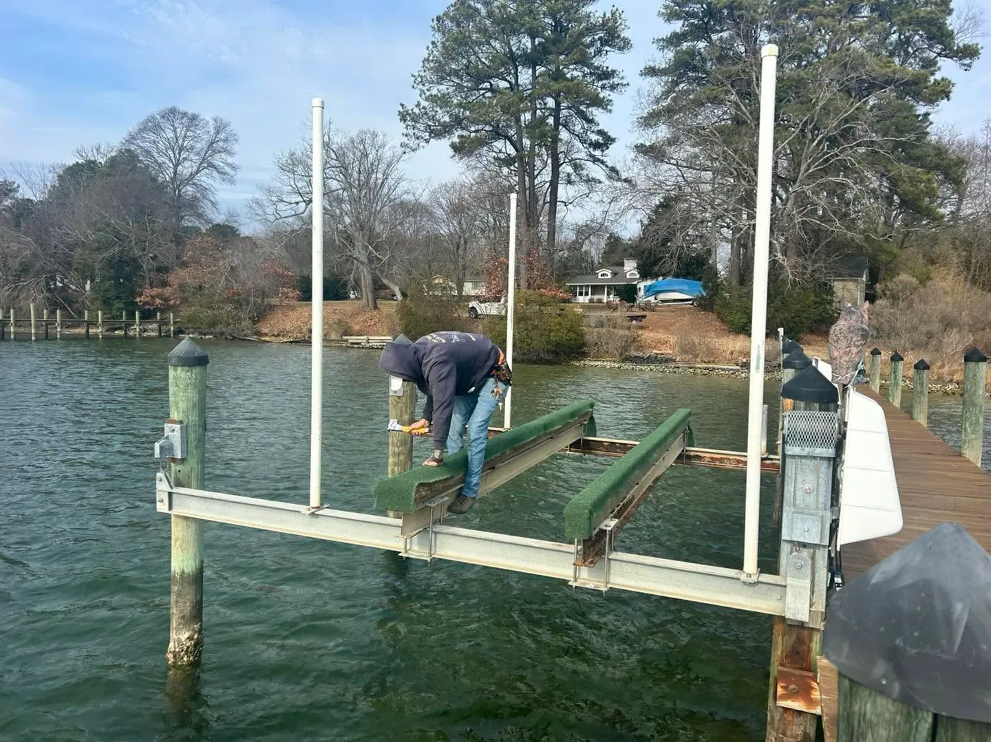 REBLS technician working on a boat lift frame over the water