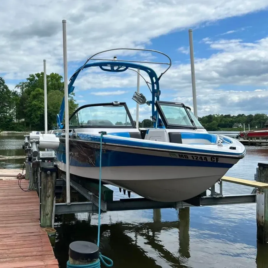 Wake boat raised on a four-pole lift on a bright day